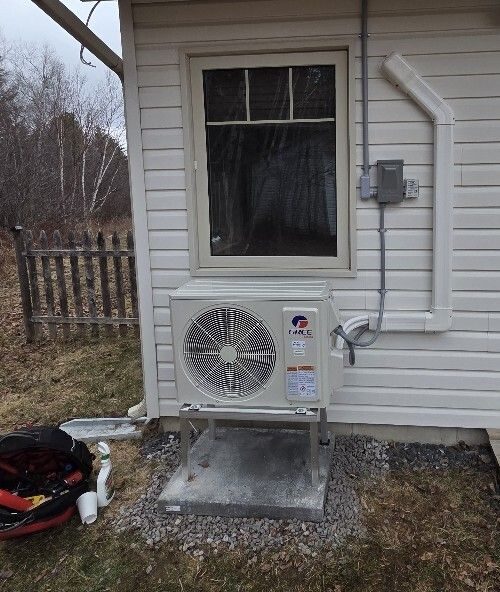 Gree outdoor heat pump unit on a metal stand below a window
